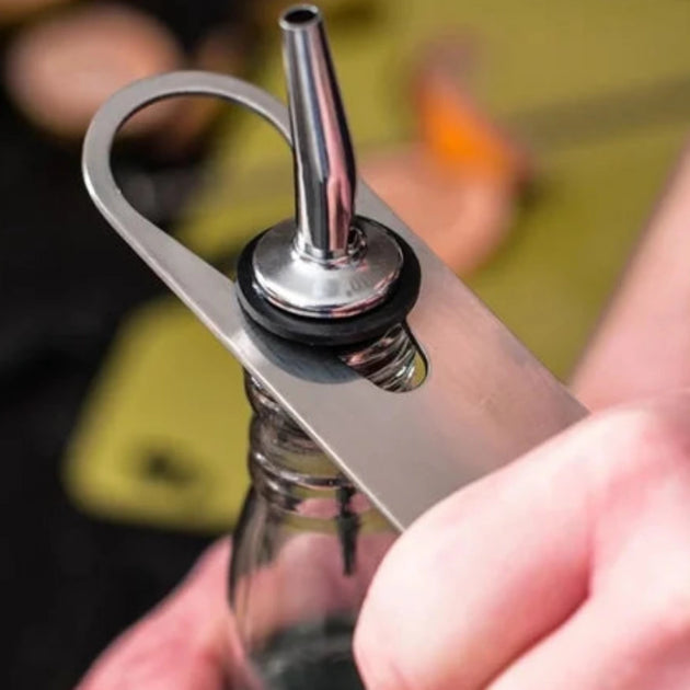 Metal bottle opener with hook being used on a bottle.